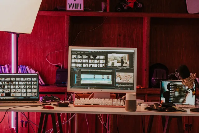 A professional video editing workspace featuring monitors, keyboard, and microphones in a studio setting. Aufnahme, Bearbeitung und Veröffentlichung als getrennte Aufgaben betrachten