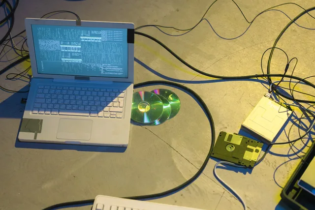 An overhead view of a vintage electronics setup featuring a laptop and disks with tangled cables. Eine Ausweichlösung für einen Streamausfall planen