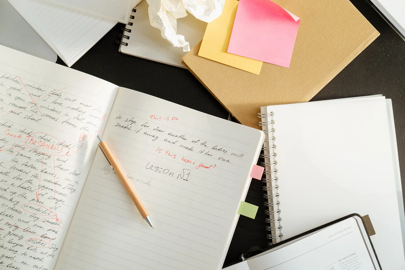 A cluttered desk with notebooks, sticky notes, and stationery for educational purposes.
