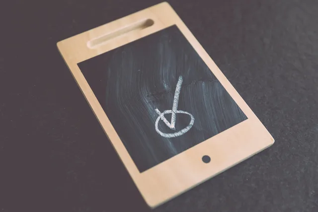 Small wooden chalkboard tablet with a checkmark drawn on it, suitable for concepts like success and approval. Freigaben für einen gemeinsamen Entwurf organisieren