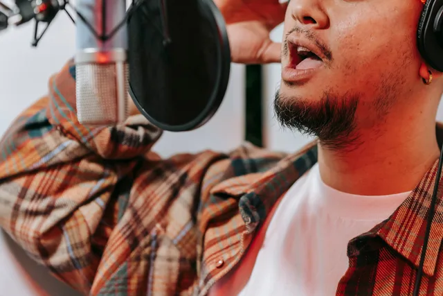 A male singer recording vocals with a condenser microphone and pop filter in a studio. Störgeräusche mit realen Testaufnahmen bewerten